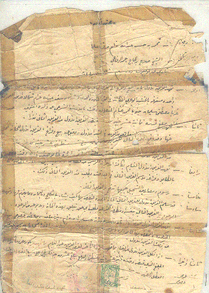 Handwritten Arabic land contract, folded, torn and patched with brown tape, with a green revenue stamp at the bottom